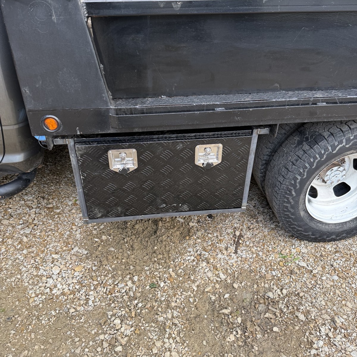 Diamond plate storage box mounted below a trailer bed