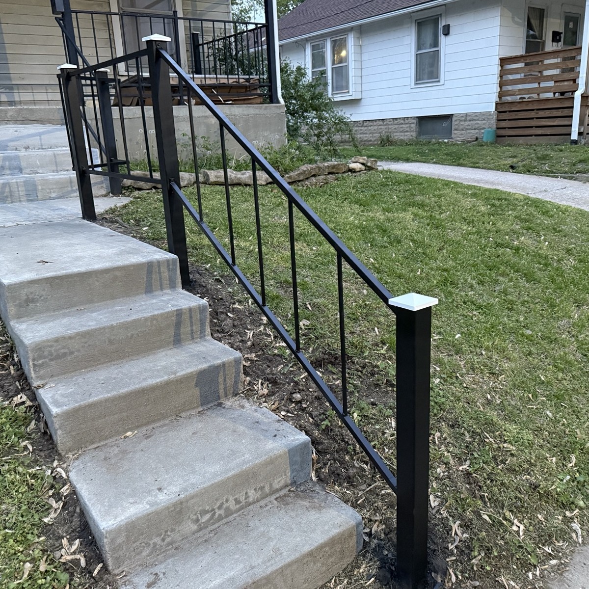 Black steel handrail installed beside concrete steps