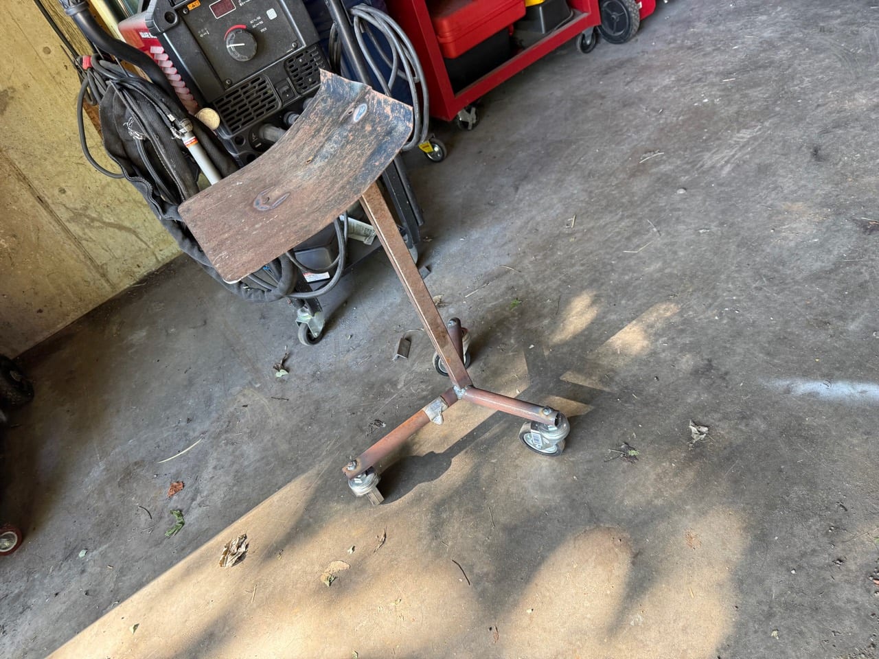 Rolling welded steel work stand with caster base in a garage shop